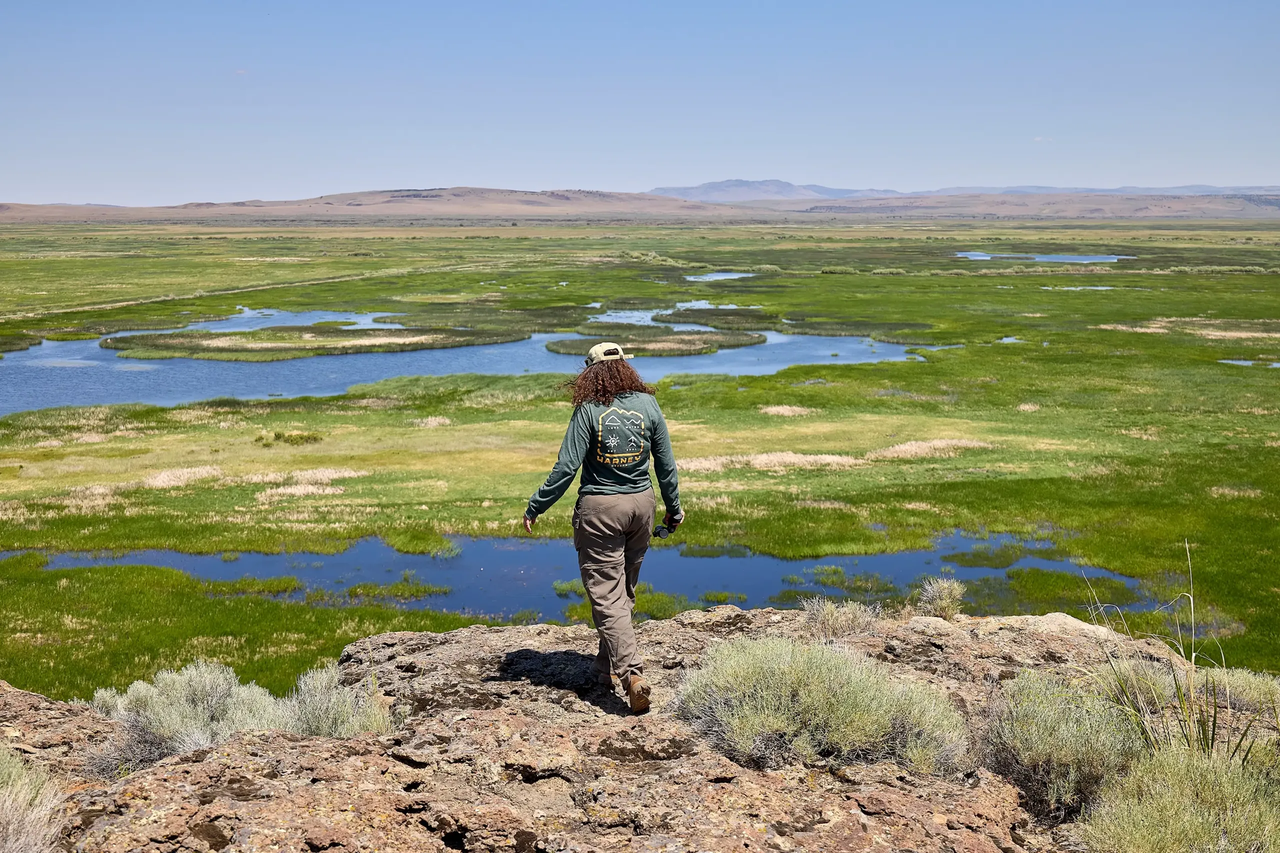 A woman walking along a ledge overviewing the Harney County flyway