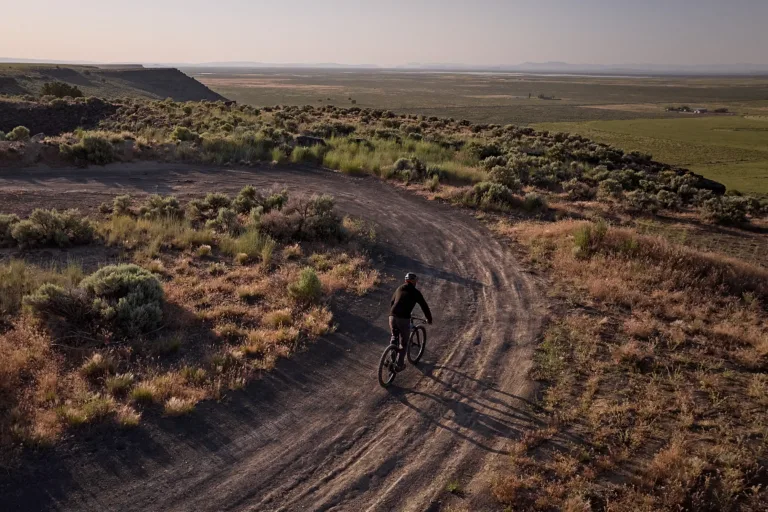 A bicyclist on a dirt path by the edge of a cliff overlook