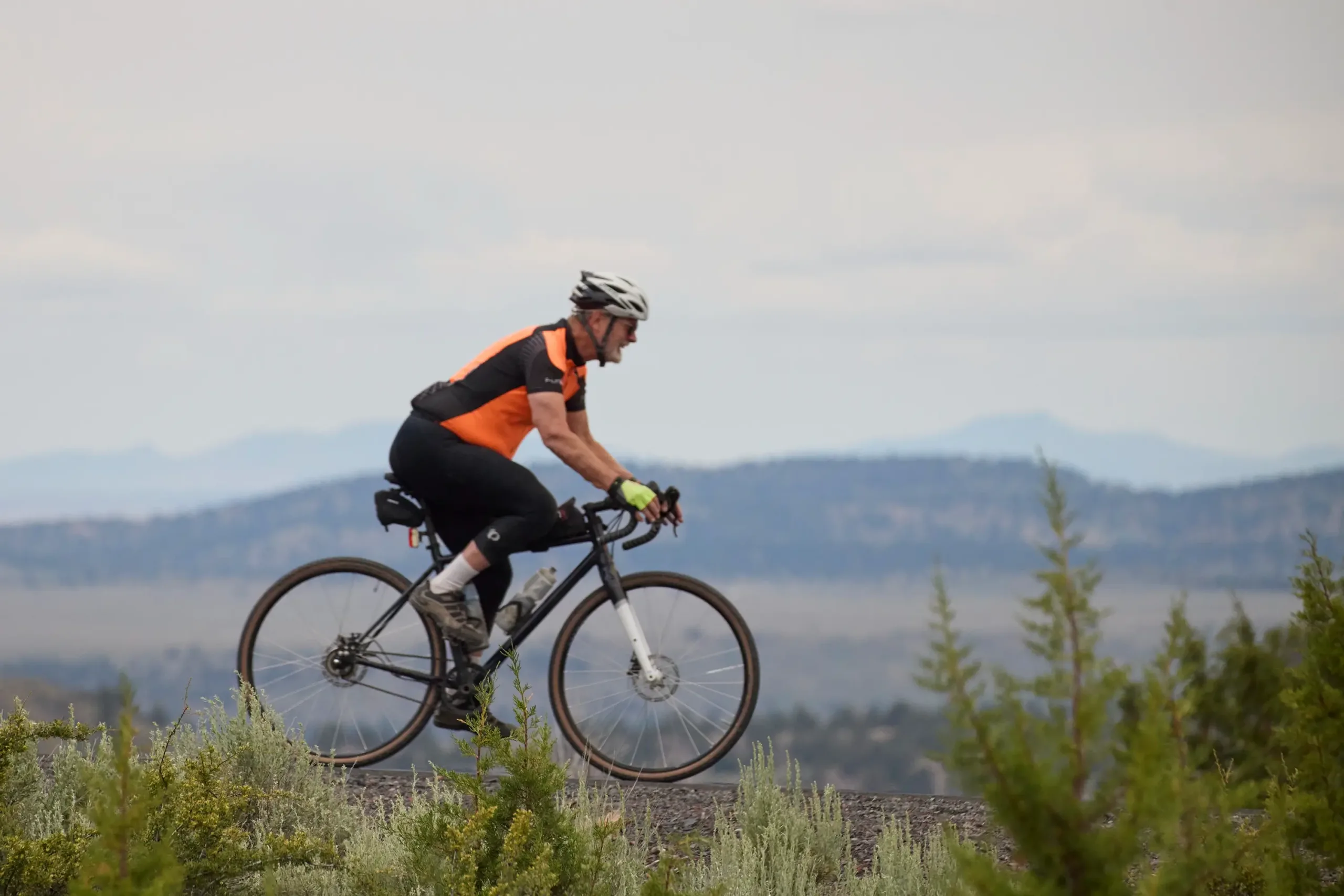 A bicyclist from the side, with a mountain range in the background