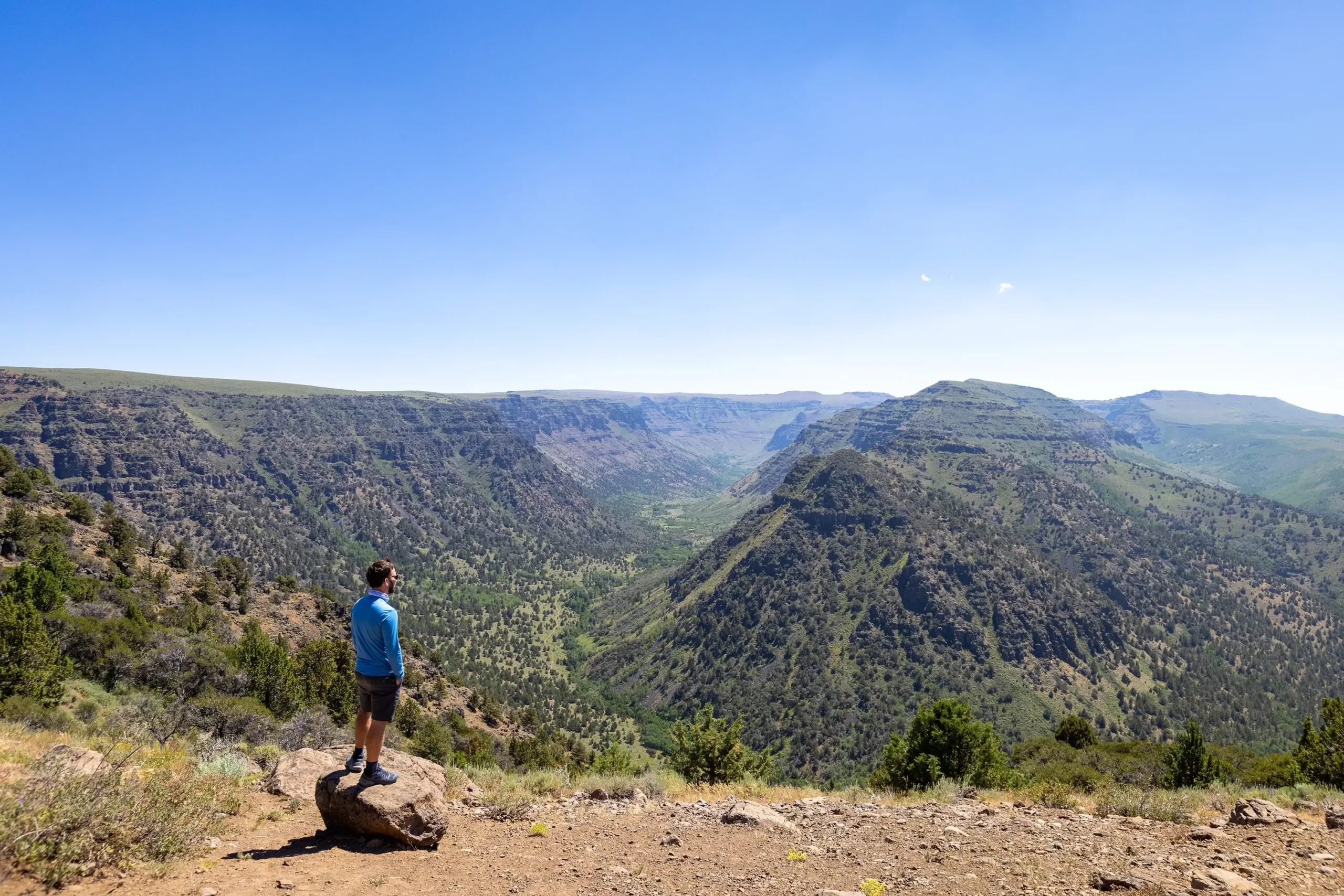 A man standing on a rock admiring a canyon view